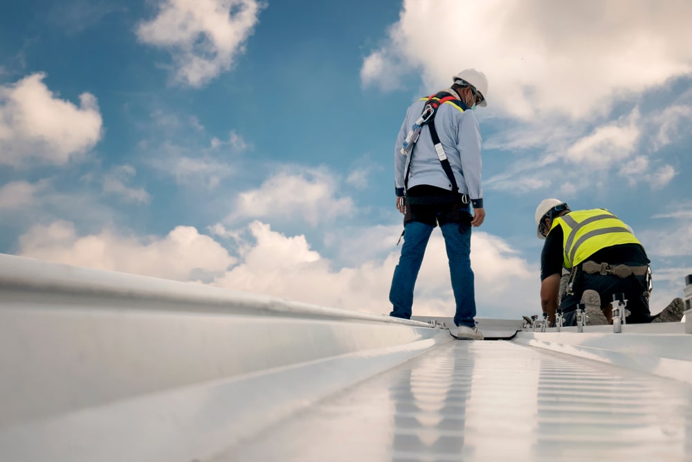 A professional roof inspection examining custom valley flashings and metal sheets for signs of surface corrosion and leaks.